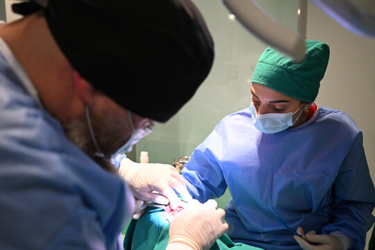 Surgeons Performing Delicate Surgery in Hospital Operating Room With Nurse Assistant and Surgical Team