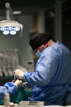 Dentist Performing Dental Surgery in Clinic With Surgical Mask and Gloves During Patient Procedure