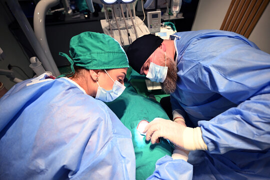 Dental Surgery Team Performing Oral Surgery in Clinic With Surgical Masks and Sterile Gloves