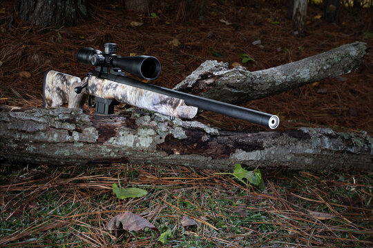 High powered rifle resting on a log outdoors