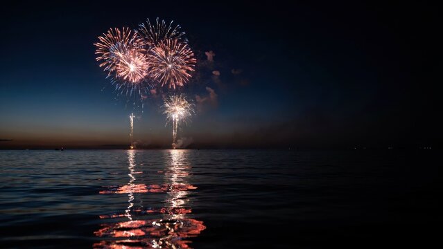 Fireworks display illuminates the dark sky over the calm water surface during a peaceful summer evening celebration.