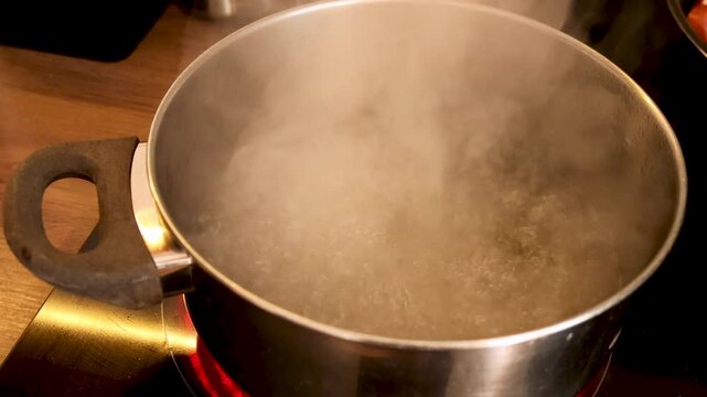 boiling water in pot for pasta cooking on stove with steam