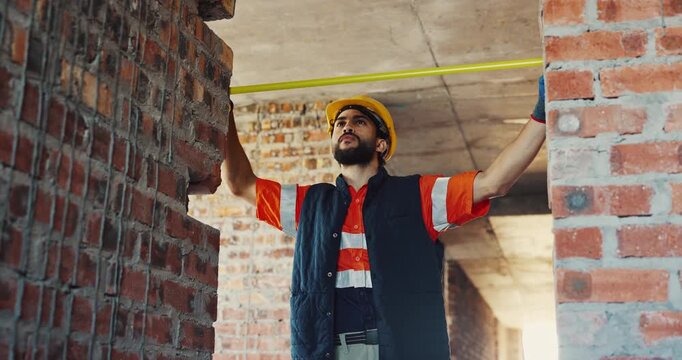 Building, engineer and tape measure at construction site for precision, dimension and brick layout. Man, doorway frame and tools for measurement, structure and property development or renovation
