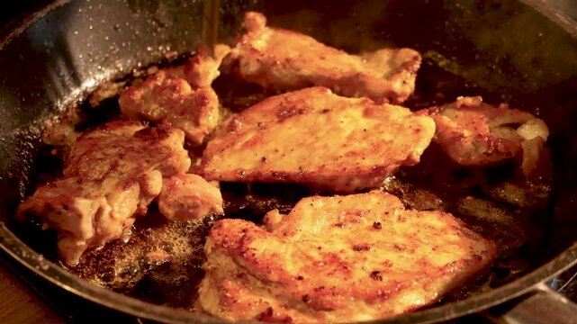 chicken frying in hot oil inside pot on stove in kitchen close up, chicken pieces frying in hot oil in metal pot with bubbles and cooking texture