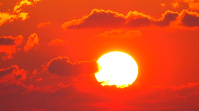 Sunset Sky Clouds vibrant red sunset with large glowing sun and dramatic moving clouds in the atmospheric evening sky
