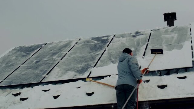 A man clears snow from solar panels. Selective focus.