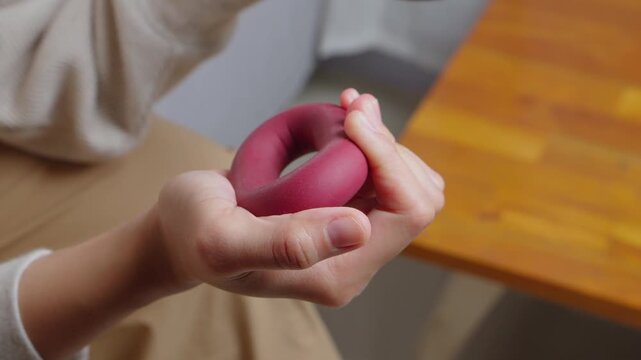 Woman's hand using a hand grip strengthener for forearm exercise while sitting on the couch