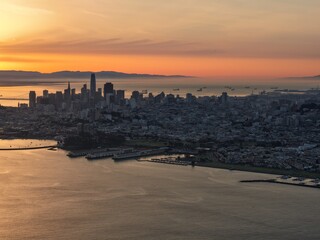 Fototapeta premium Golden sunset over San Francisco skyline with Bay Bridge and glowing bay waters. g.