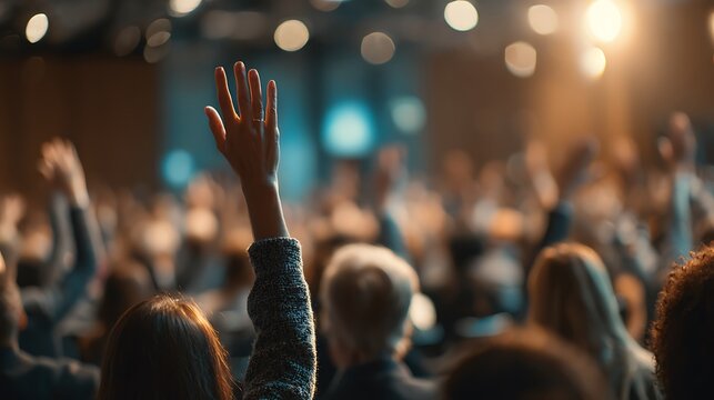 Audience members raising hands at a conference event.