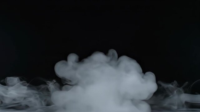 White smoke wafts up against dark background, flowing and swirling in an ethereal, graceful motion