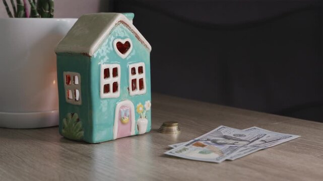 Man adding money to savings stack near house model on table