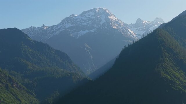 Snow capped Himalayan mountain peak towering above pine covered valleys and rugged ridgelines near Sar Pass Trek between Grahan Village and Sosan in the Parvati Valley, Kasol, Himachal Pradesh, India