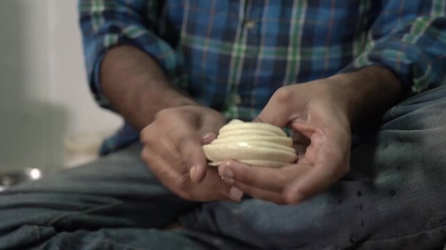 Hands kneading dough for making flaky laccha paratha during food preparation.