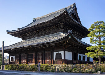 Fototapeta premium Large traditional wooden temple with an ornate tiered roof stands under a clear blue sky in Kyoto.