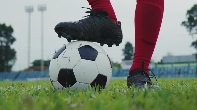 Slow motion close-up of a soccer player placing a foot on the ball before kickoff on a grass field. Match preparation, focus, teamwork and competitive sports concept