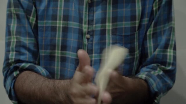 Hands kneading dough for making flaky laccha paratha during food preparation.