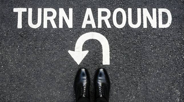Businessman shoes standing on asphalt road with turn around text and u turn sign