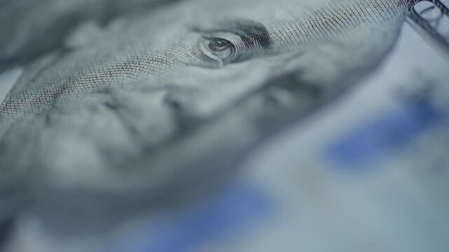 Dim lit hundred dollar bill scan light, low key illumination glances over microprinting and security ribbon, cool blue tones, slow pan, tense surveillance mood