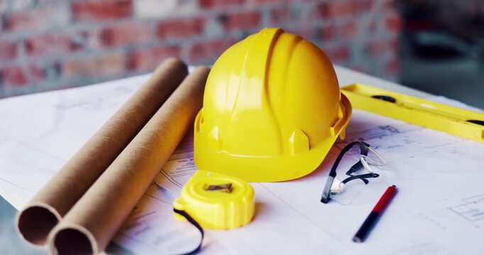Construction, blueprint and tools with helmet on table for development, layout or floor plan. Infrastructure documents, engineering and safety ppe, drawing equipment or building design at empty site