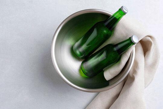 Two Green Glass Bottles in Metal Bowl