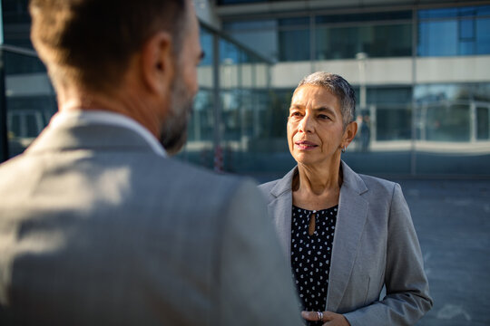Senior businesswoman talking with colleague outside office
