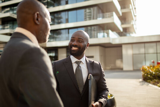 Two businessmen greeting outside modern office building