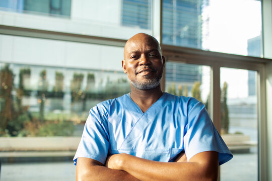 Smiling male healthcare professional in scrubs at hospital lobby