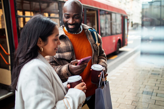 Friends with coffee waiting at city bus stop