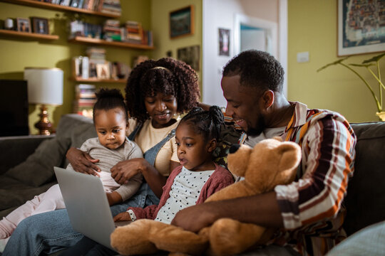 Parents and daughters using a laptop on the living room sofa