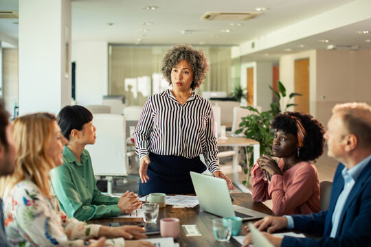 Confident manager leading diverse team meeting in modern office