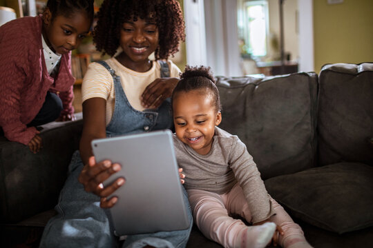 Mother and children using tablet on sofa at home
