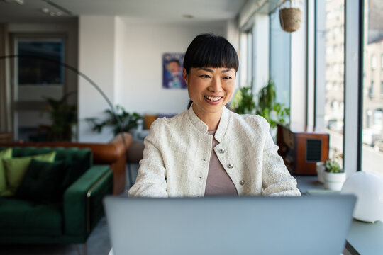 Smiling businesswoman working on laptop in modern office