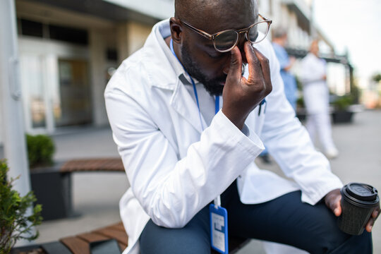 Exhausted doctor rubbing eyes outside hospital during break