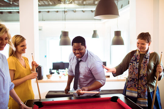 Coworkers playing pool in a modern office