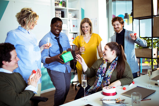 Coworkers celebrating birthday with gift in modern office