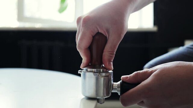 Barista tamping espresso grounds in a portafilter for a perfect coffee shot