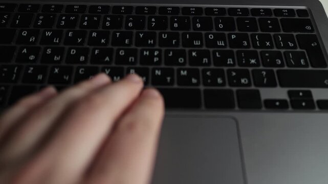Close-up of hands typing on a laptop keyboard with Cyrillic and Latin characters