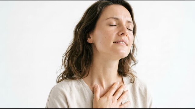 Woman practicing deep breathing exercise to reduce anxiety and stress. Girl taking a mindful breath with hand on chest. Mental health and relaxation therapy session.