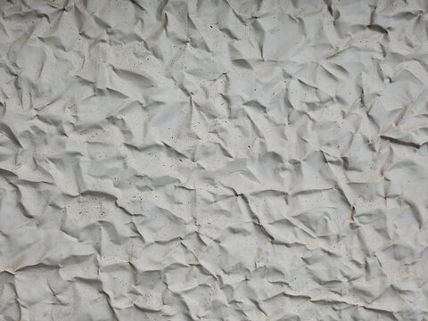 Abstract background texture of crumpled white paper or wrinkled light gray concrete surface with fine speckles and sharp creased folds.
