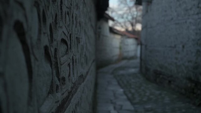 An old cobblestone street with high stone fences on both sides.
