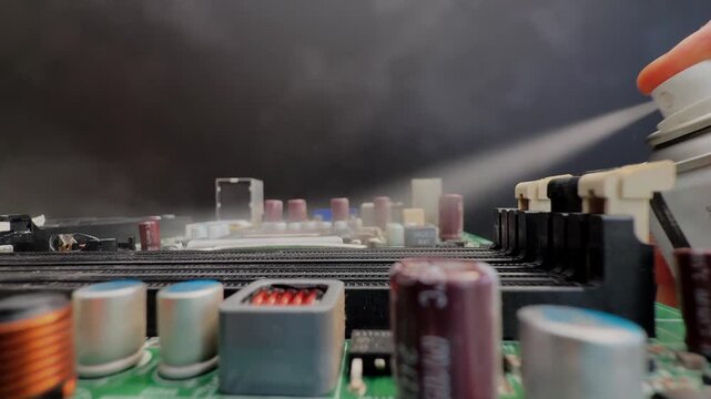Closeup of a hand holding a canister while spraying cleaning and lubricating fluid, under pressure across an electrical circuit of machine components.