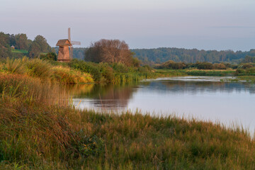 Obraz premium An ancient wooden windmill on the banks of the Sorot River on a foggy summer morning, Mikhailovskoye, Pushkinskiye Gory, Pskov region, Russia