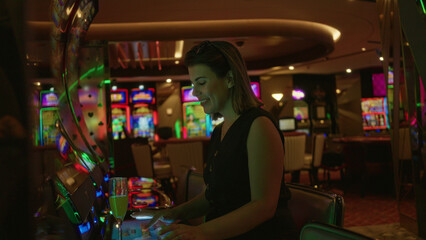 Fototapeta premium Woman cheering at slot machine in casino building, fists raised and smiling at winning spin; joy luck winning.