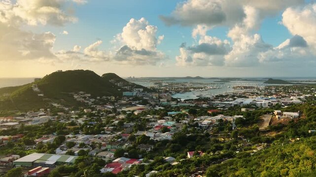 Aerial view of Cole Bay town and Simpson Bay Lagoon on the Dutch side of Saint Martin island in the Caribbean Sea. Drone flight captures the lush green hills and coastal.
