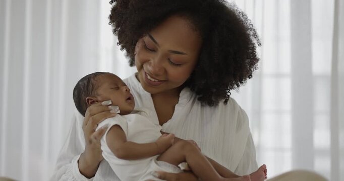 Close up portrait of beautiful young African American  mother holding sleep newborn baby in hospital bed room. Healthcare medical love black afro woman lifestyle mother's day, breast with copy space. 