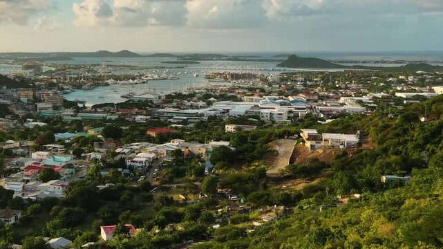 Aerial view of Cole Bay town and Simpson Bay Lagoon on the Dutch side of Saint Martin island in the Caribbean Sea. Drone flight captures the lush green hills and coastal community.