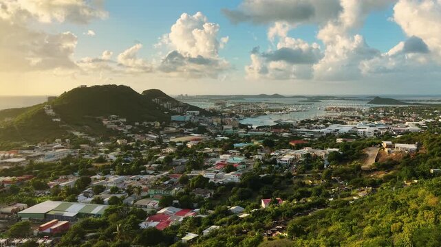 Aerial view of Cole Bay town and Simpson Bay Lagoon on the Dutch side of Saint Martin island in the Caribbean Sea. Drone flight captures the lush green hills and coastal community.