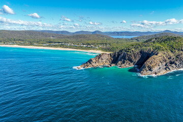 Naklejka premium Aerial scene capturing the rocky headland of Charlotte Head and Boomerang Beach near Pacific Palms, NSW, Australia. Surrounded by clear turquoise waters, rugged coastal formations and sandy shoreline.