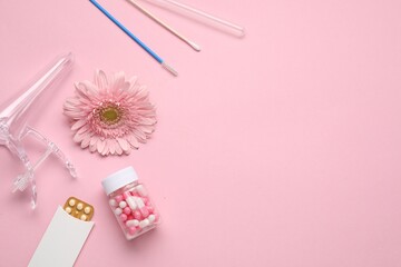 Naklejka premium Flat lay composition with gynecological examination kit and gerbera flower on pink background, space for text