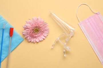 Naklejka premium Flat lay composition with gynecological examination kit and gerbera flower on pale orange background